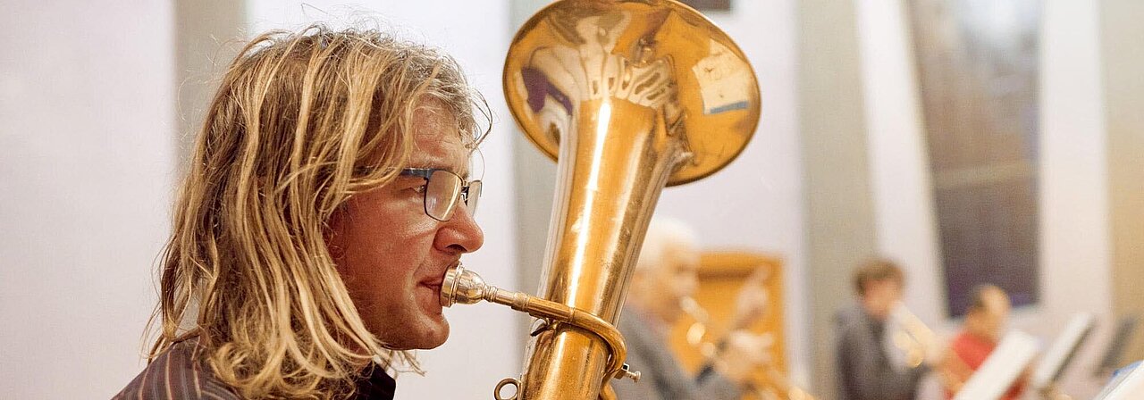 Ein Mann spielt Horn in einem Orchester.